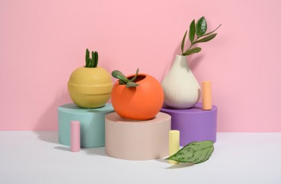 Colorful ceramic vegetable-shaped vases on pastel blocks, decorative home decor, trendy plant holders, vibrant arrangement for interior design, modern aesthetic.