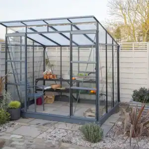 Aluminum greenhouse with transparent panels in a modern outdoor garden space, perfect for year-round gardening and plant protection.