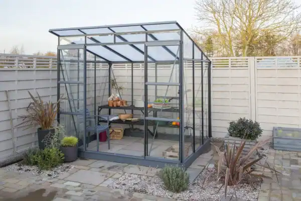 Aluminum greenhouse with transparent panels in a modern outdoor garden space, perfect for year-round gardening and plant protection.