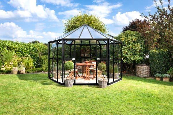 Stylish black metal and glass greenhouse set in a lush garden, perfect for growing plants, vegetables, and flowers, offering optimal conditions with durable construction.