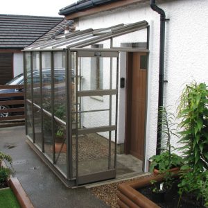 A1 Greenhouses: stylish glass garden greenhouse attached to a white house, ideal for plant protection and gardening hobby.