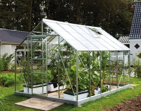 Modern glass greenhouse with lush vegetable and plant cultivation, high-quality metal framework, ideal for year-round gardening, custom-designed by A1 Greenhouses Ireland.