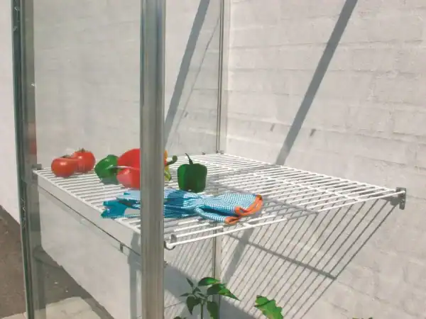 Fresh vegetables and kitchen towels on a greenhouse shelf, showcasing durable structure and perfect environment for growing produce in a A1 Greenhouses structure.